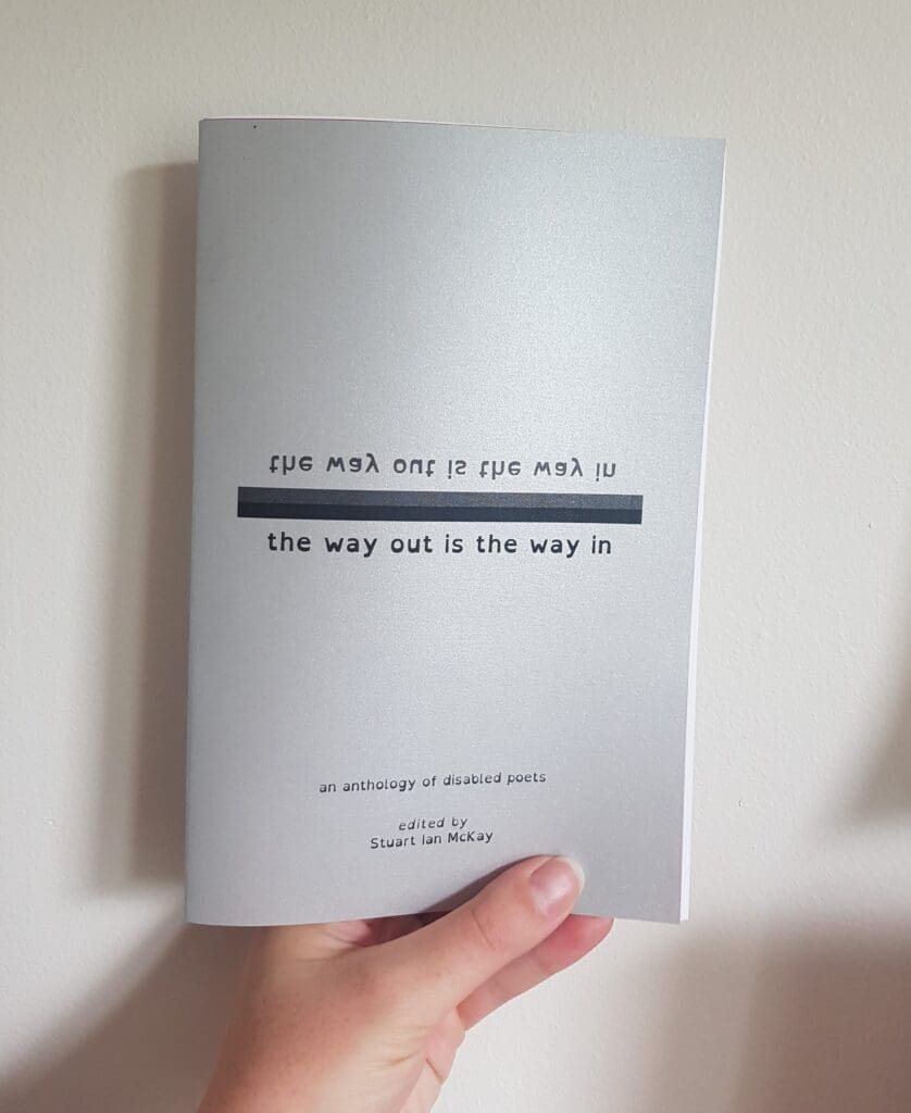 A hand holding a copy of the way out is the way in