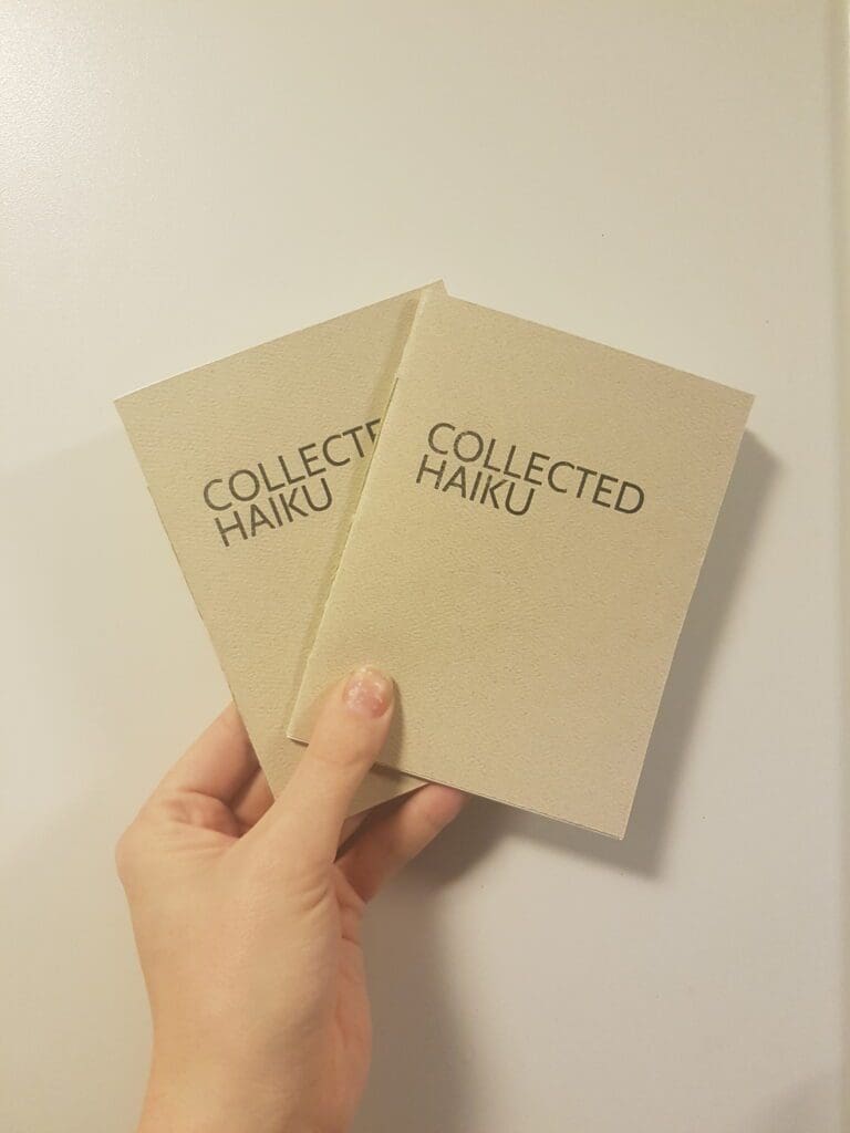 A hand holding two copies of Collected Haiku
