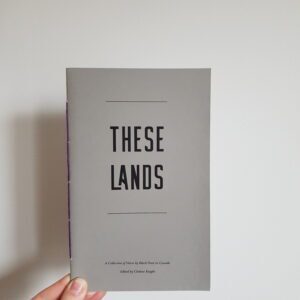 A hand holding a copy of These Lands