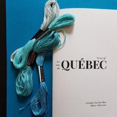 A copy of Voices of Quebec with several bundles of embroidery closs